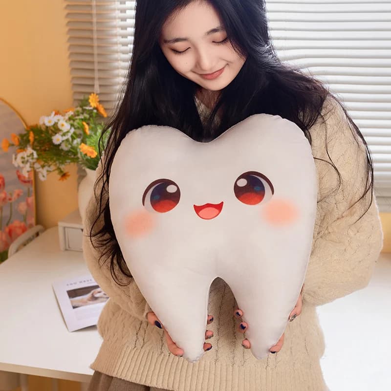 Brinquedo de pelúcia em forma de dente branco com olhos e boca sorridentes