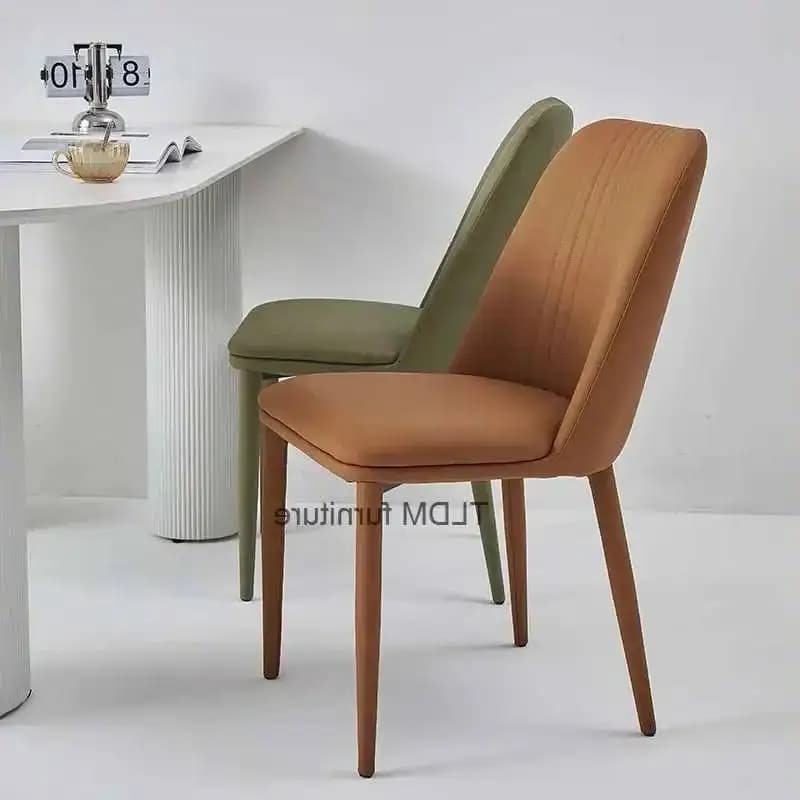 Cadeiras modernas de jantar com couro sintético bege e verde, posicionadas em um ambiente minimalista.