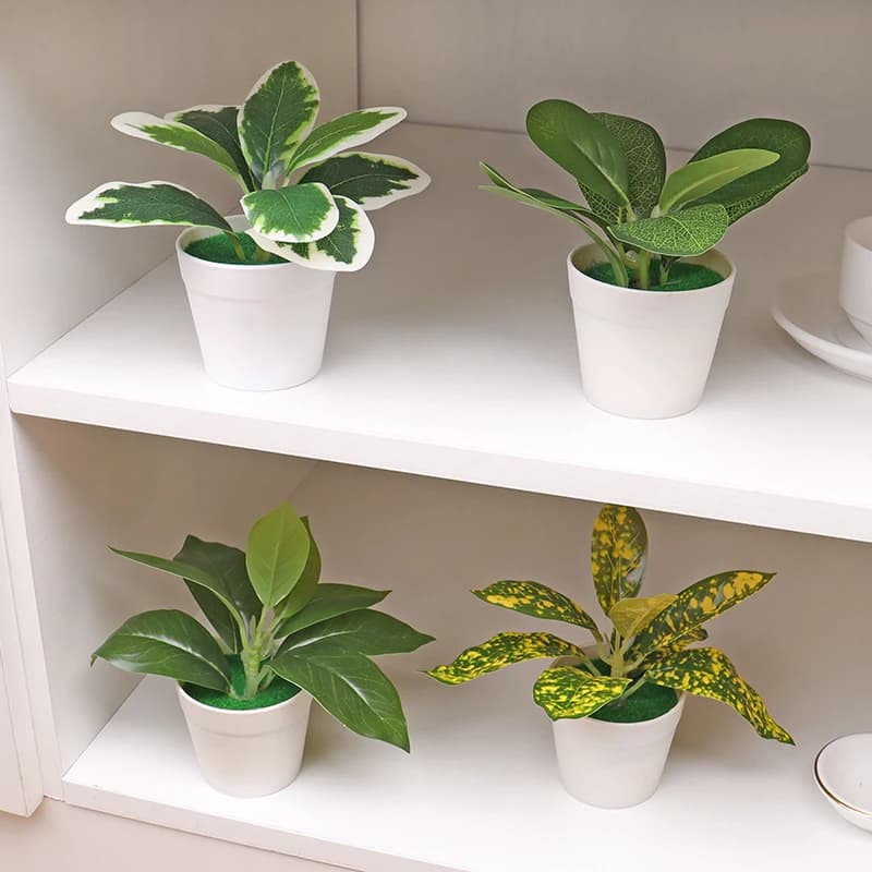 Quatro plantas artificiais em vasos brancos em uma prateleira branca