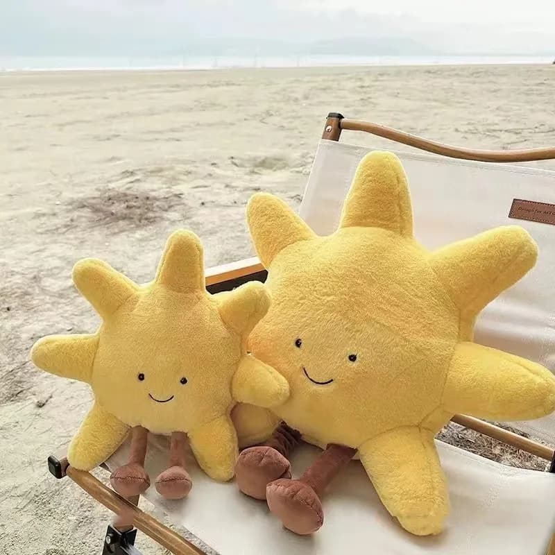 Almofada de pelúcia amarela em forma de sol com rosto sorridente e almofada de lua branca com rosto feliz