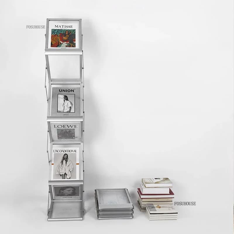 Estante porta-revistas retrô A4 dobrável em alumínio prata com revistas e livros ao lado em fundo branco