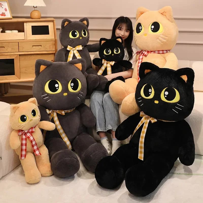Almofada de pelúcia em forma de gato preto com olhos amarelos e gravata xadrez amarela e preta, em um sofá branco.