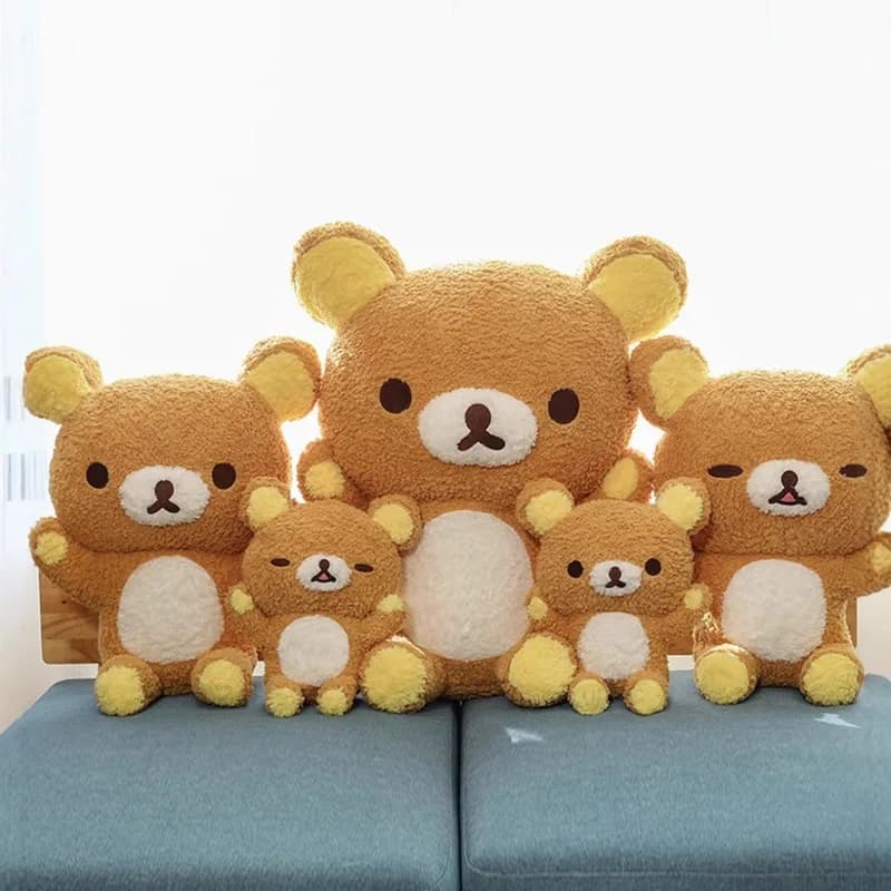 Cinco ursos de pelúcia Rilakkuma marrons com barriga branca alinhados em sofá azul
