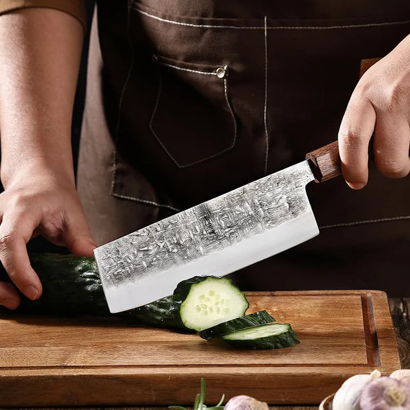 Faca Kiritsuke WXCOO com lâmina texturizada e cabo de madeira preta cortando pepino em tábua de madeira