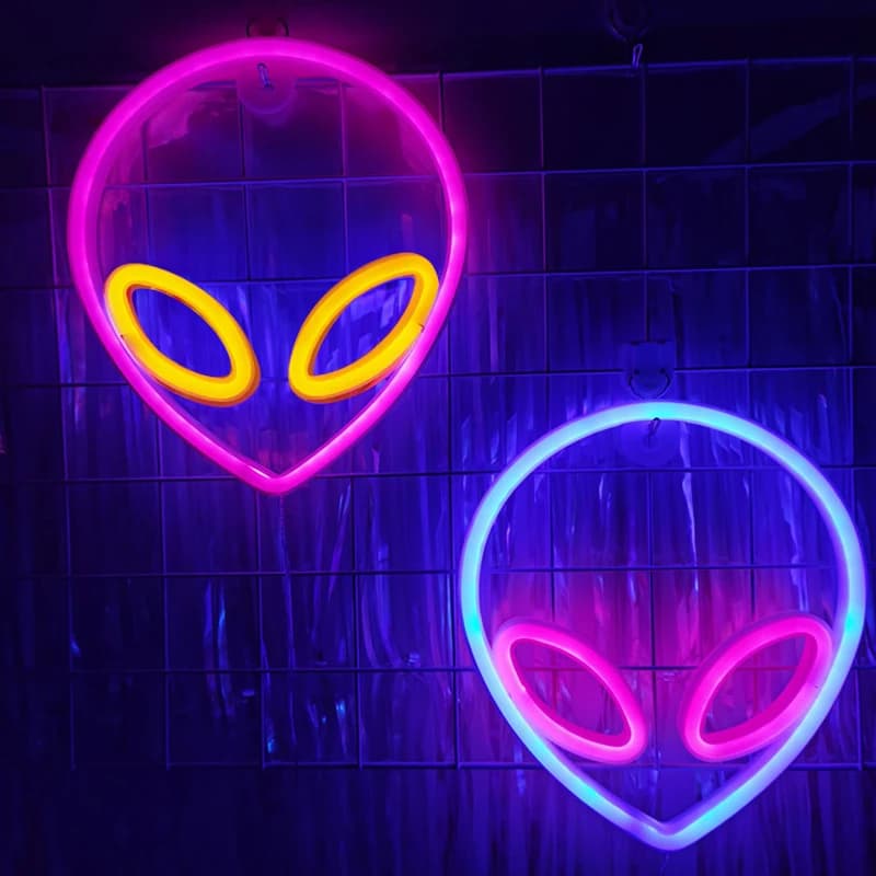 Luzes de néon alienígenas em forma de OVNI, uma rosa e uma azul, iluminadas contra um fundo escuro.