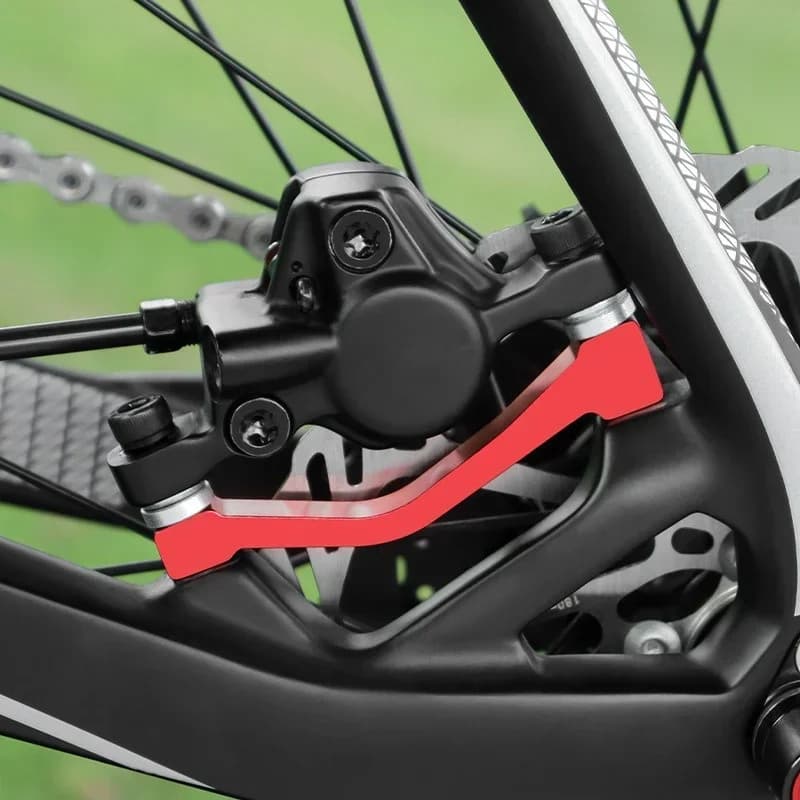 Adaptador vermelho de montagem de pinça de freio a disco instalado em bicicleta com quadro preto e disco de freio