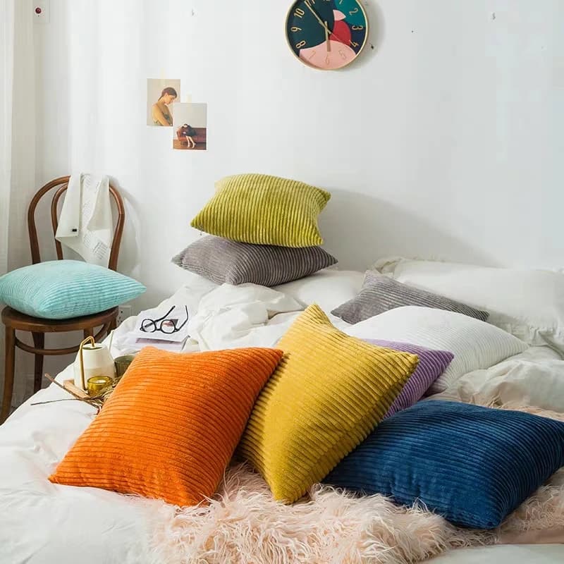 Várias capas de almofada de veludo plush macio coloridas em cama branca com decoração moderna