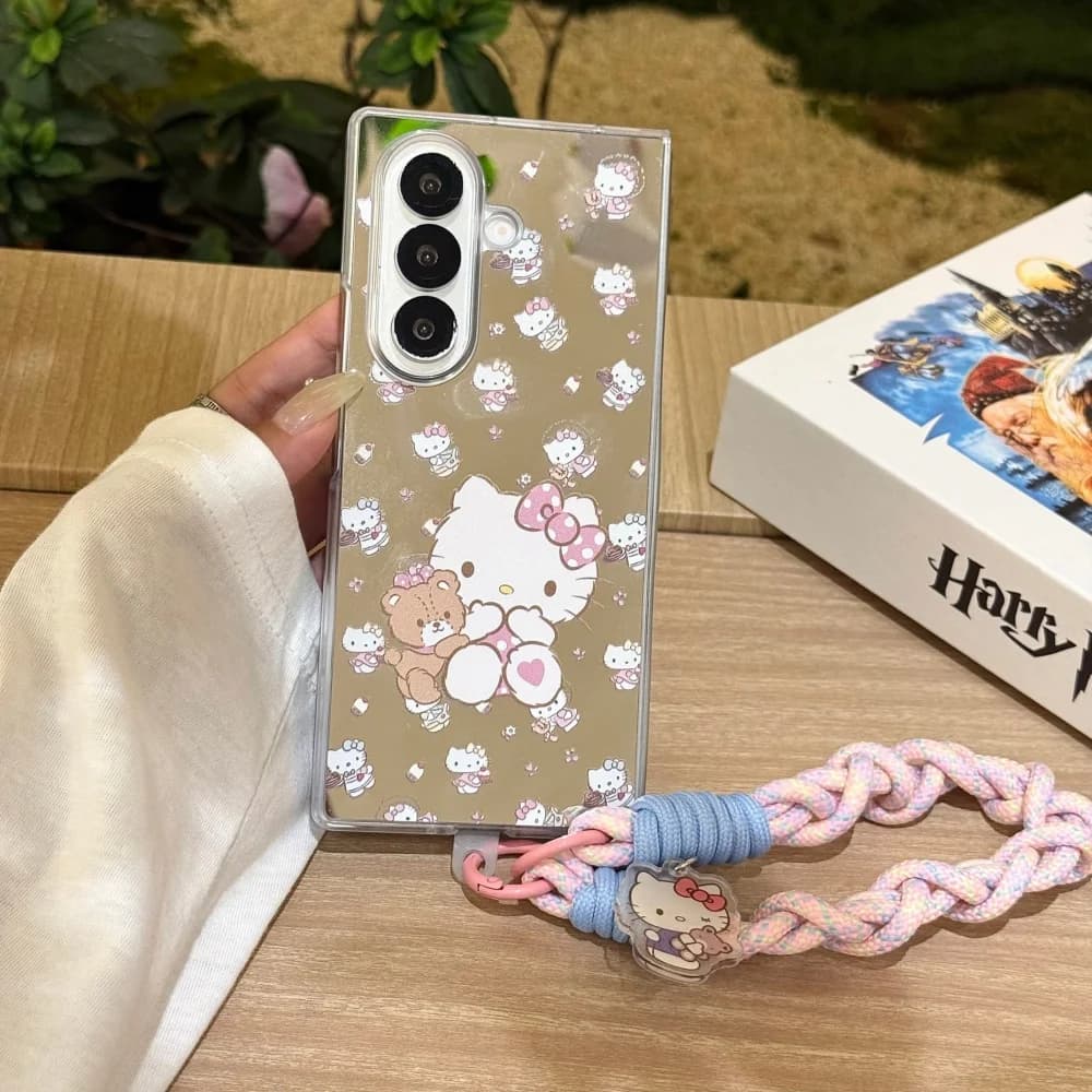 Capa para celular Galaxy Z Fold 7 bege claro com estampa Hello Kitty segurando ursinho e cordão trançado colorido