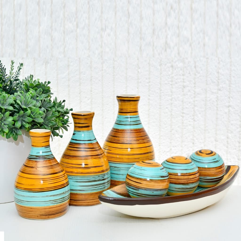 Sete vasos decorativos em cerâmica laranja e azul-turquesa com esferas decorativas e planta verde