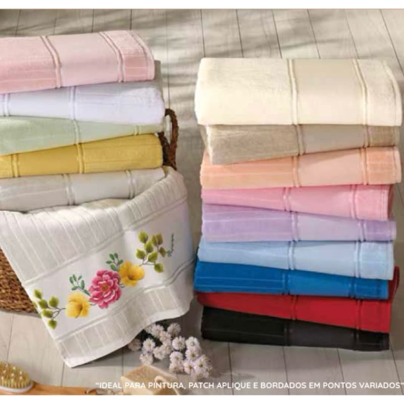 Toalhas de banho e rosto em velour, cores variadas, design floral e listras, dispostas em pilhas