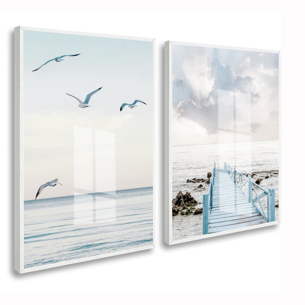 Quadros decorativos com mar e ponte azul, moldura branca, vidro, céu azul, gaivotas voando, água calma, rochas na margem.