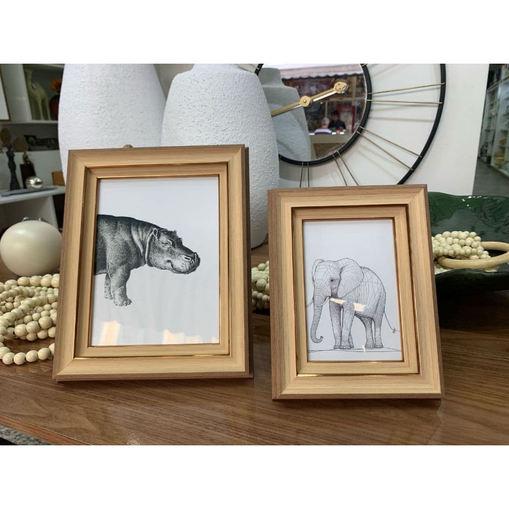 Porta-retratos com molduras douradas, um com hipopótamo e outro com elefante, em fundo dec.