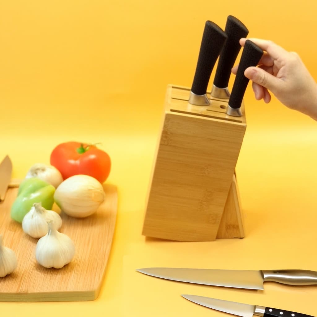 Suporte de bambu para facas e tesouras com alças pretas e pontas metálicas, fundo amarelo com vegetais.