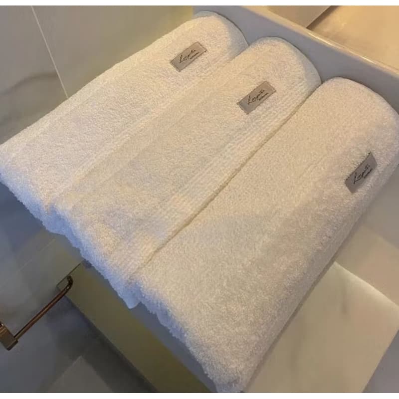 Kit de 3 toalhas de banho brancas com etiquetas Led, empilhadas em compartimento de armário
