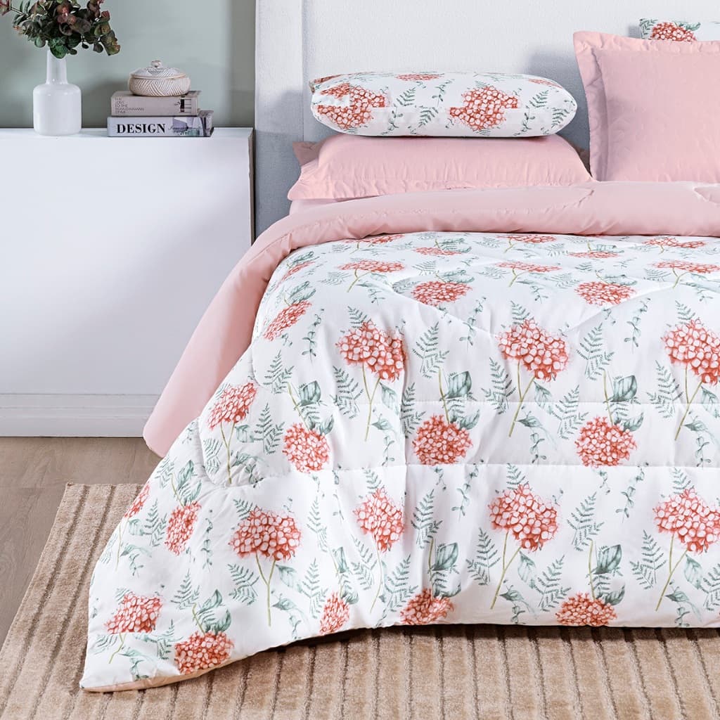 Edredom de casal floral com flores vermelhas e folhas verdes, sobre cama com almofadas rosa