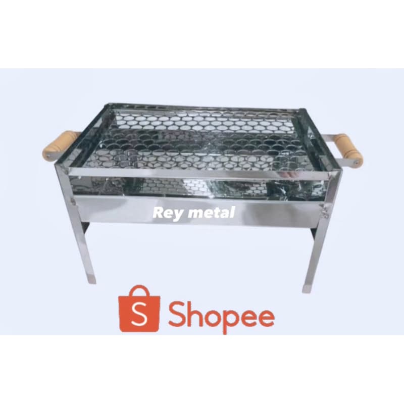 Churrasqueira inox moderna com grelha hexagonal e alças de madeira, fundo branco