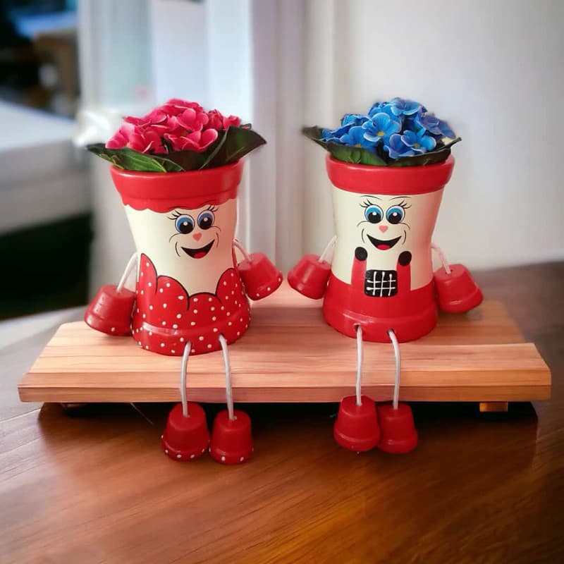 Vasos articulados decorativos com flores vermelhas e azuis sobre base de madeira