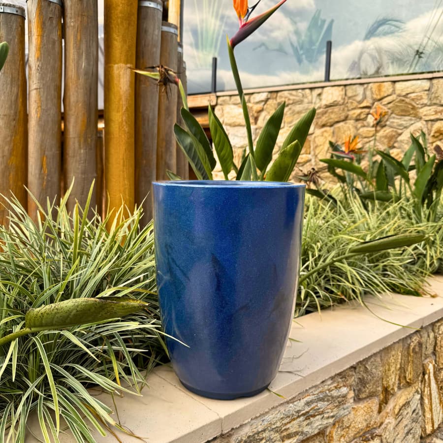 Vaso grande azul polietileno marmoreado para plantas com flores tropicais ao fundo