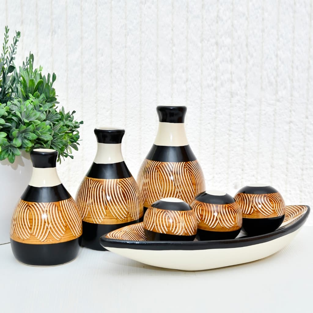 Conjunto decorativo de cerâmica com sete peças, vasos grandes e pequenos com estampas geométricas em marrom e preto.