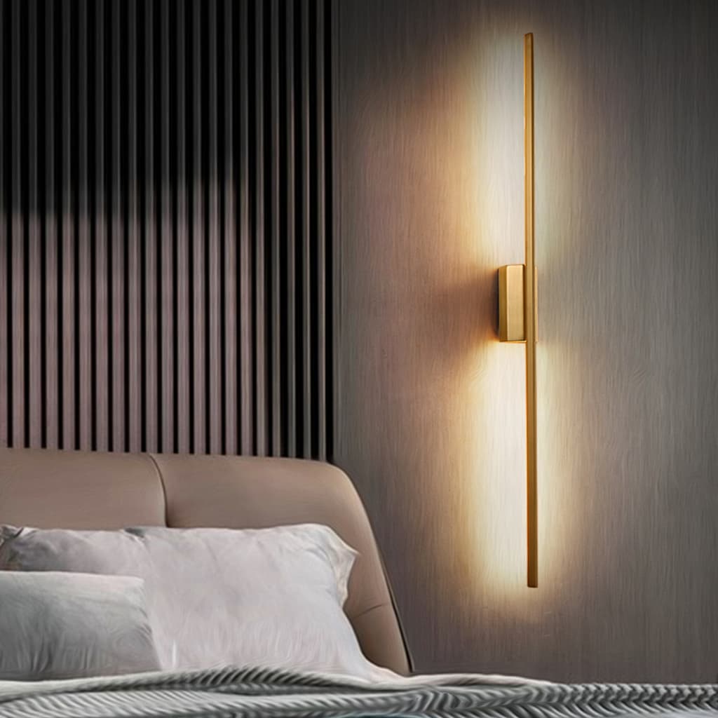 Luminária LED linear dourada de 1 metro acesa na parede ao lado da cama.