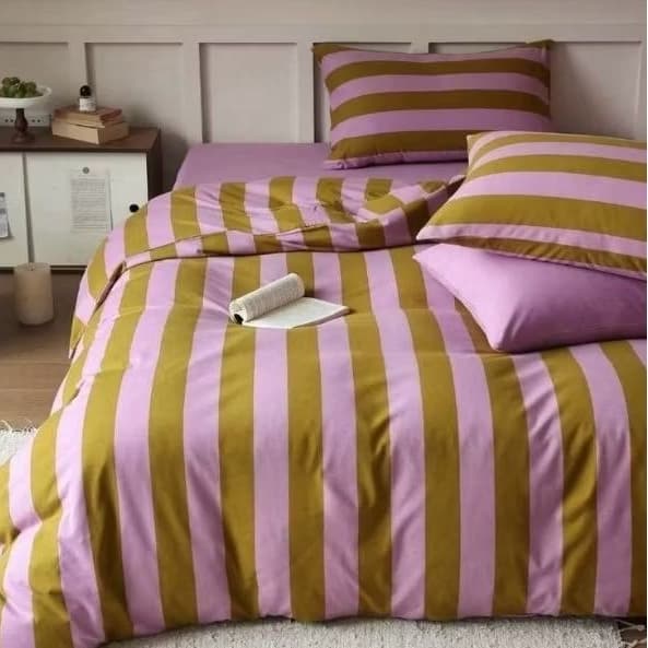 Edredom listrado rosa e marrom em uma cama arrumada com travesseiros