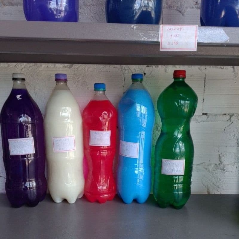 Cinco garrafas de produtos de limpeza em cores diferentes dispostas em uma prateleira