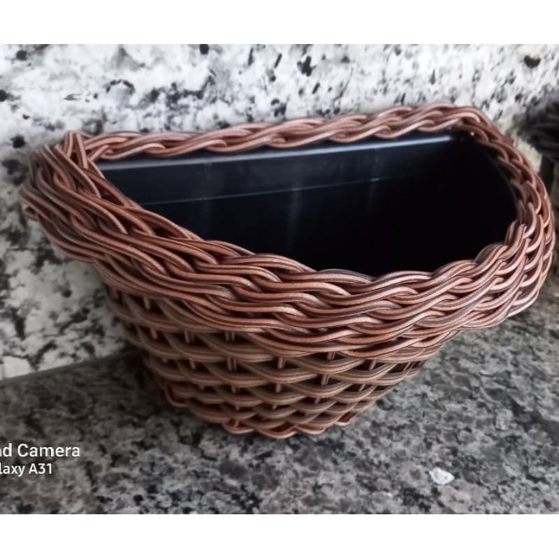 Cesta de parede marrom com design de vime e compartimento preto para plantas