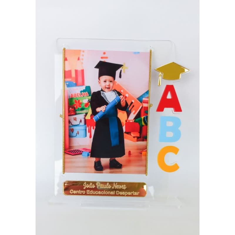 Porta retrato acrílico transparente com foto de criança graduada segurando diploma
