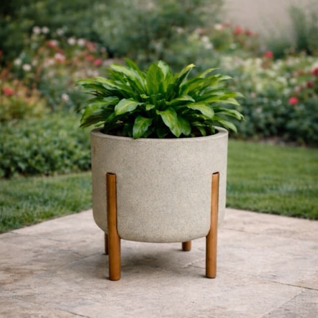 Vaso cilíndrico cinza claro com pés de madeira para plantas em um jardim