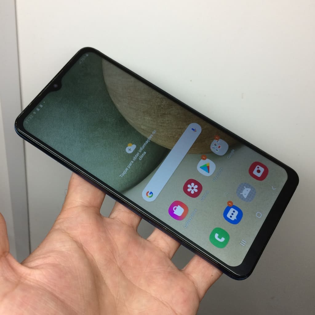 Samsung Galaxy A12 64GB em mãos, smartphone com tela de ícones e barra de busca Google