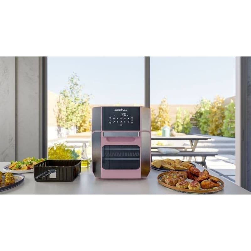 Fritadeira elétrica BRITÂNIA rosa e preta, 12L, 220V, em uma mesa com pratos de comida.