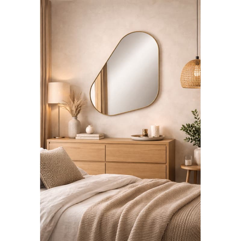Espelho orgânico com moldura dourada em quarto, refletindo cama e cômoda