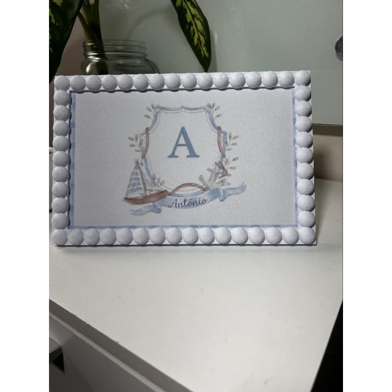 Porta retrato branco com borda de bolinhas e escudo azul com vela