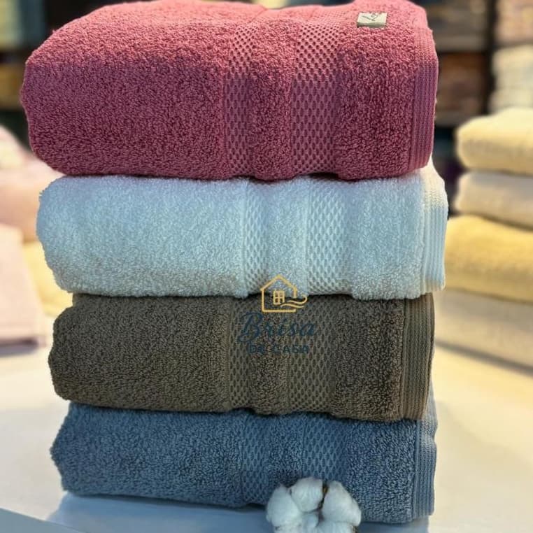 Kit de toalhas de banho felpudas com quatro peças em cores rosa, azul claro, cinza e azul marinho.