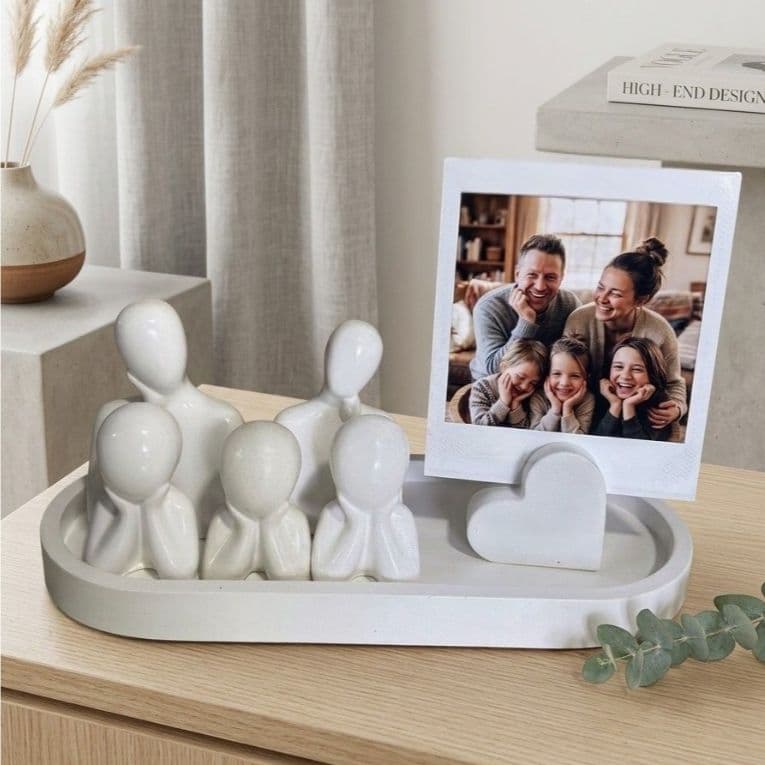 Kit decorativo familiar com porta-retrato minimalista branco em forma de coração, sobre mesa de madeira