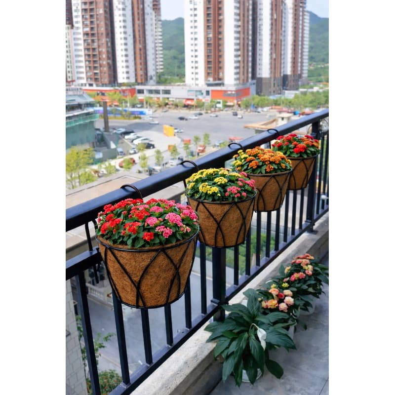 Vasos de pendurar em fibra de coco com flores coloridas em uma varanda urbana