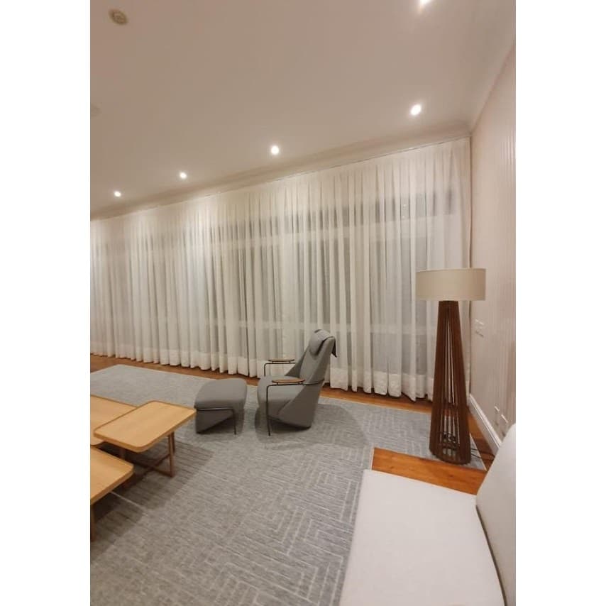 Sala de estar com cortinas brancas e mobiliário cinza