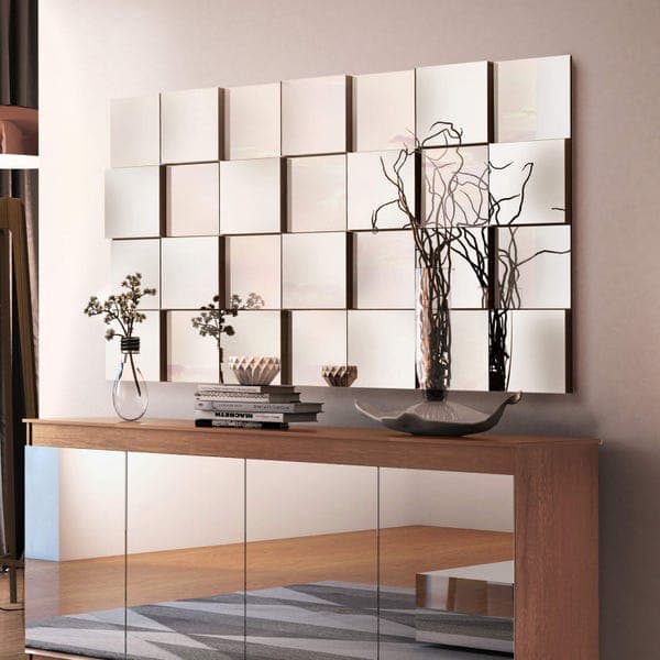 Painel decorativo 3D com 28 peças de espelhos quadrados montados em uma parede.