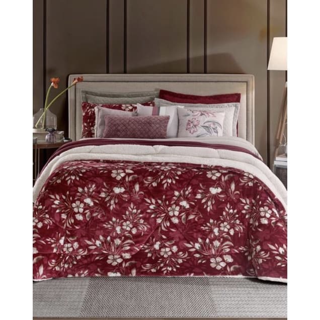 Edredom floral vermelho e branco sobre cama com almofadas vermelhas e brancas