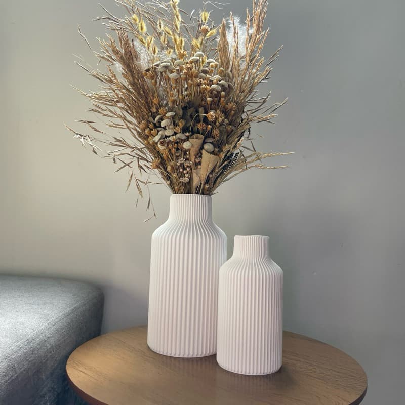 Vasos decorativos brancos estilo nórdico com flores secas em uma mesa de madeira