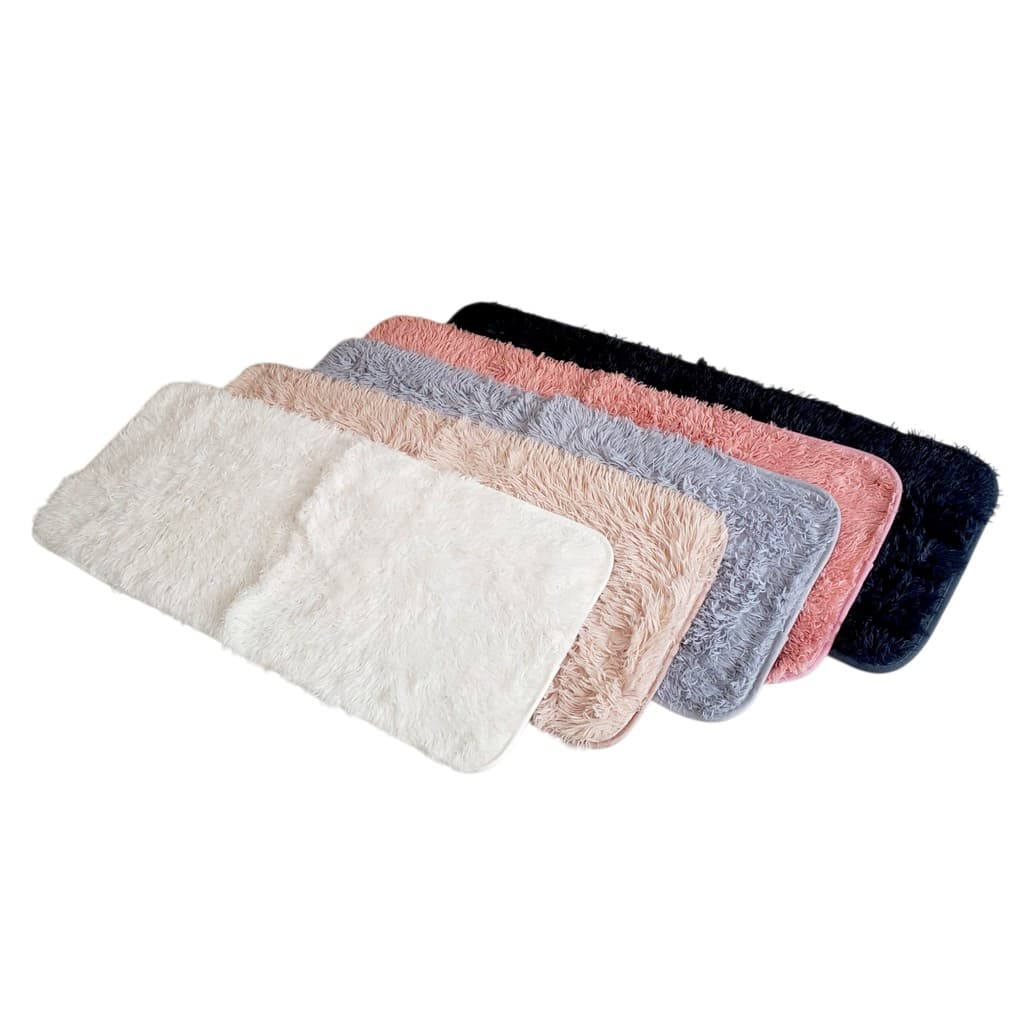Tapetes felpudos antiderrapantes em várias cores, branco, rosa, cinza e preto, dispostos em fileira.
