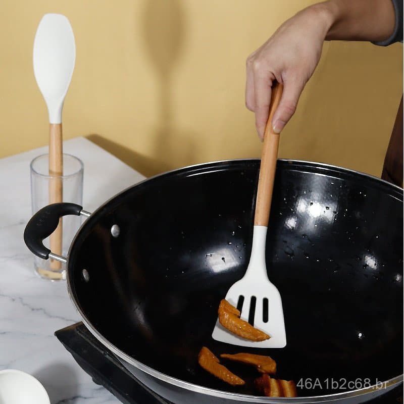 Espátula de silicone antiaderente branca sendo usada em uma frigideira preta para cozinhar