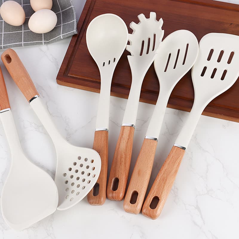 Utensílios de cozinha de silicone com cabo de madeira brancos em fundo marmorizado