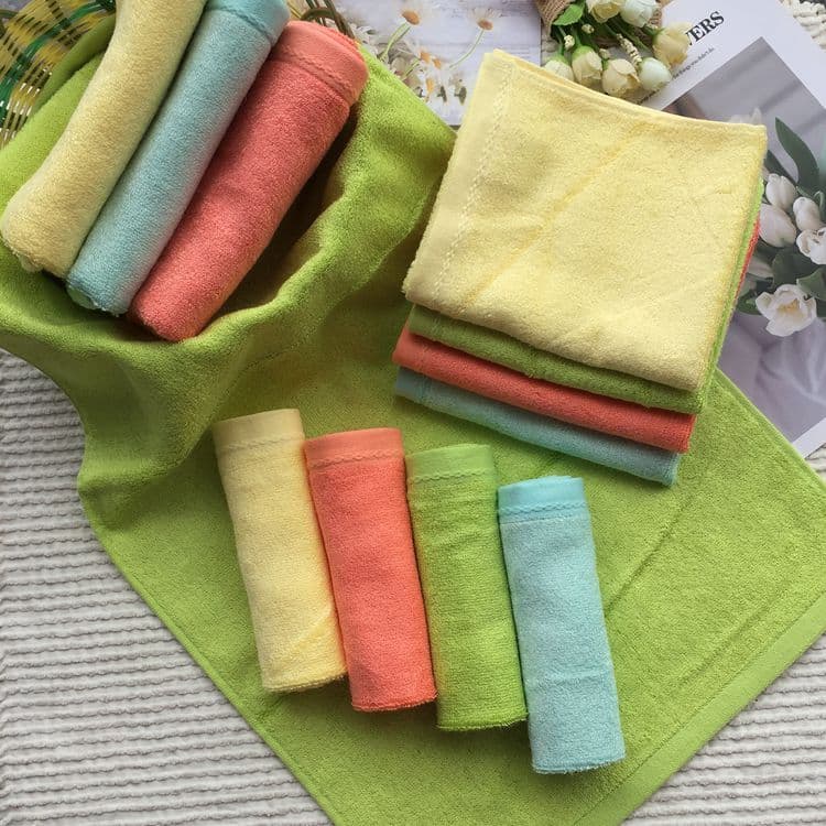 Toalhas de fibra de bambu em cores vibrantes sobre fundo verde com flores brancas