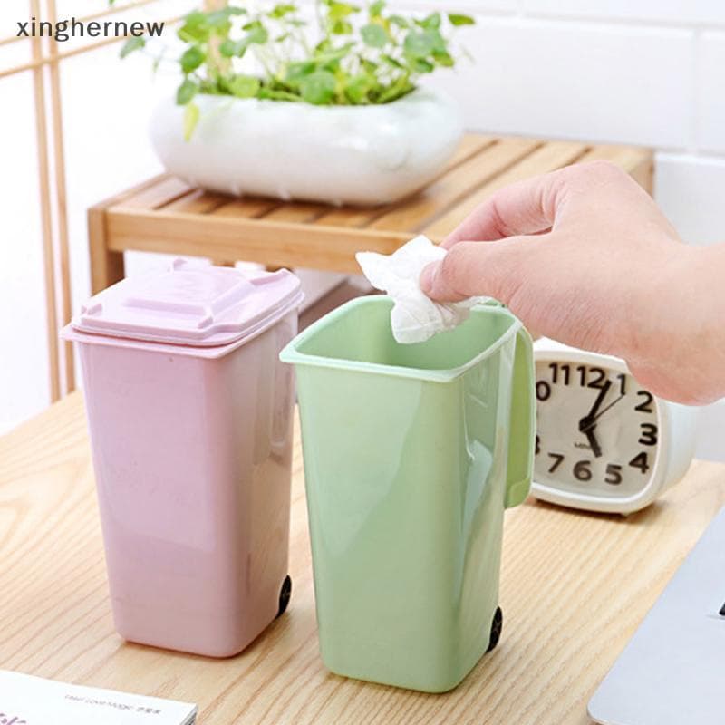 Lixeiras de mesa Xinghernew com tampa, rosa e verde, em fundo de madeira com relógio e planta