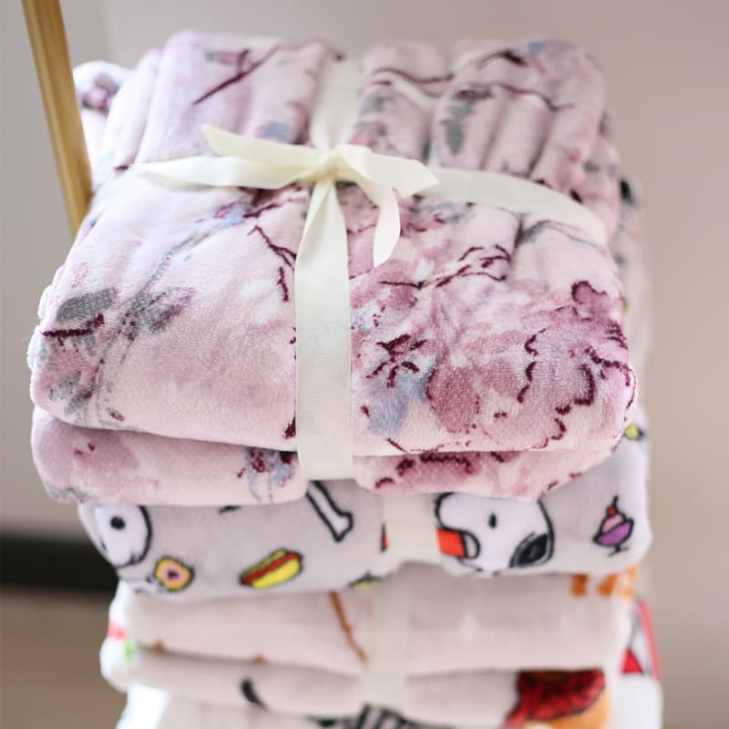 Cobertores infantis de flanela em padrão floral rosa e branco, empilhados e embrulhados com fita