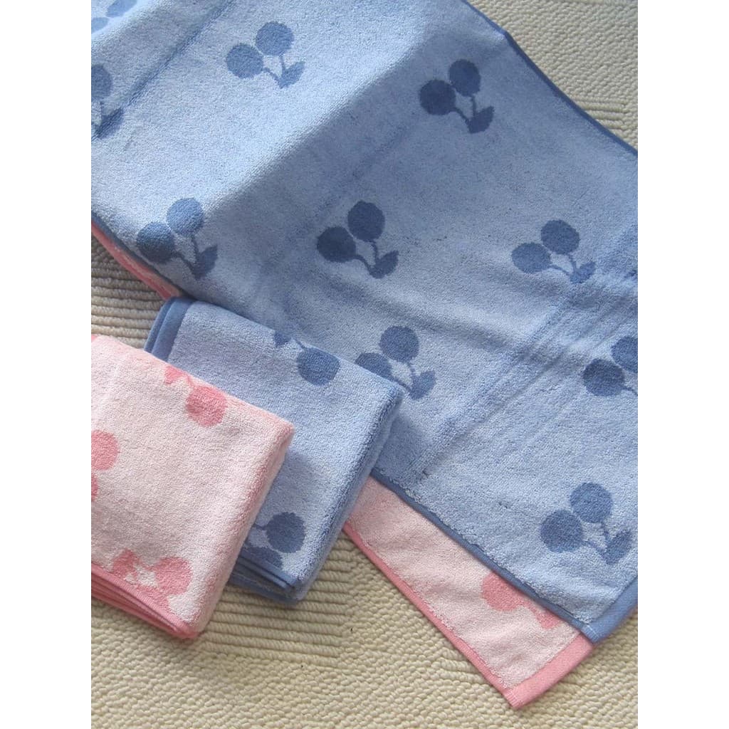Toalhas de banho com padrão floral em azul e rosa, sobre fundo neutro.
