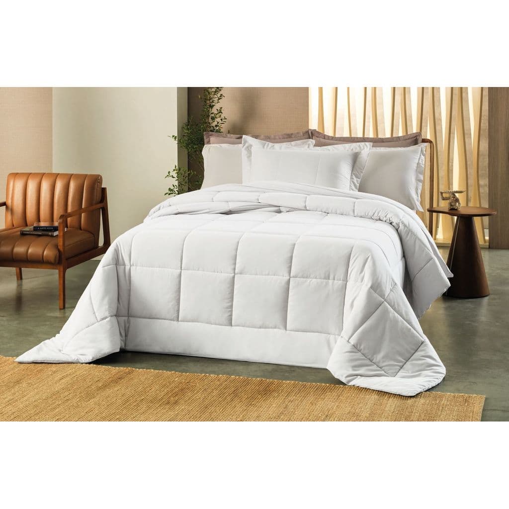 Edredom king branco em um quarto com cama de solteiro, coberta por edredom branco, tapete marrom, parede clara e cortina amarela