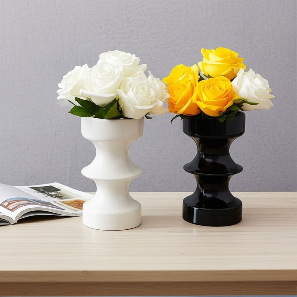 Vasos decorativos de cerâmica branco e preto com flores, estilo moderno, sobre uma mesa de madeira.