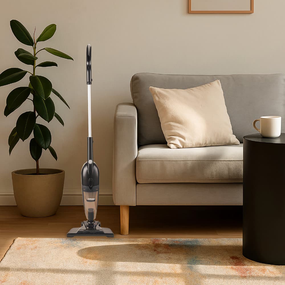 Aspirador vertical Itatiaia com reservatório 1,2L em pé, cor preto e cinza, em um ambiente de estar com sofá e mesa de centro.